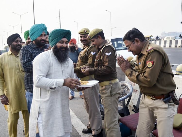 New Delhi: Farmers offer sweets to policemen as they celebrate after Samyukta Kisan Morcha announced to call off the farmers agitation, at Ghazipur border in New Delhi, Thursday, December 9, 2021. (PTI Photo/Ravi Choudhary)(PTI12_09_2021_000173B)